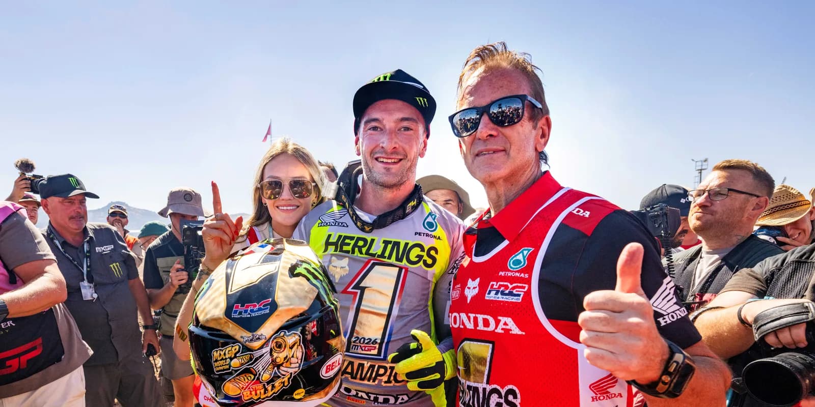 Jeffrey Herlings in the paddock holding his helmet after clinching the 2026 MXGP title, in a jersey reading HERLINGS and a number board reading 1, 2026 MXGP champion