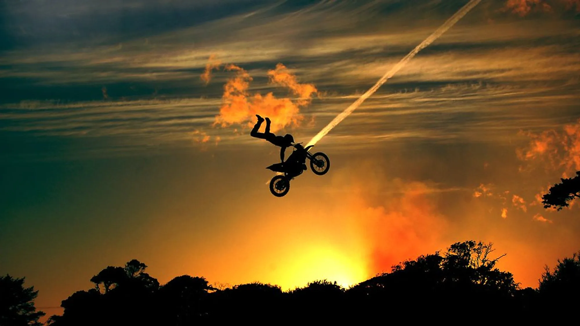 Sunset silhouette of a rider mid-jump