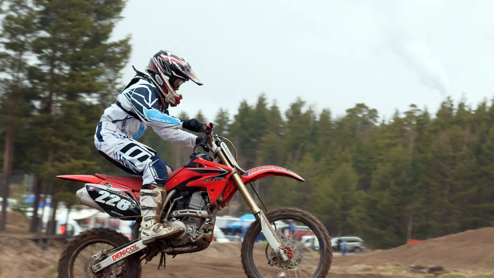 A factory motocross bike lofting the front wheel out of a corner