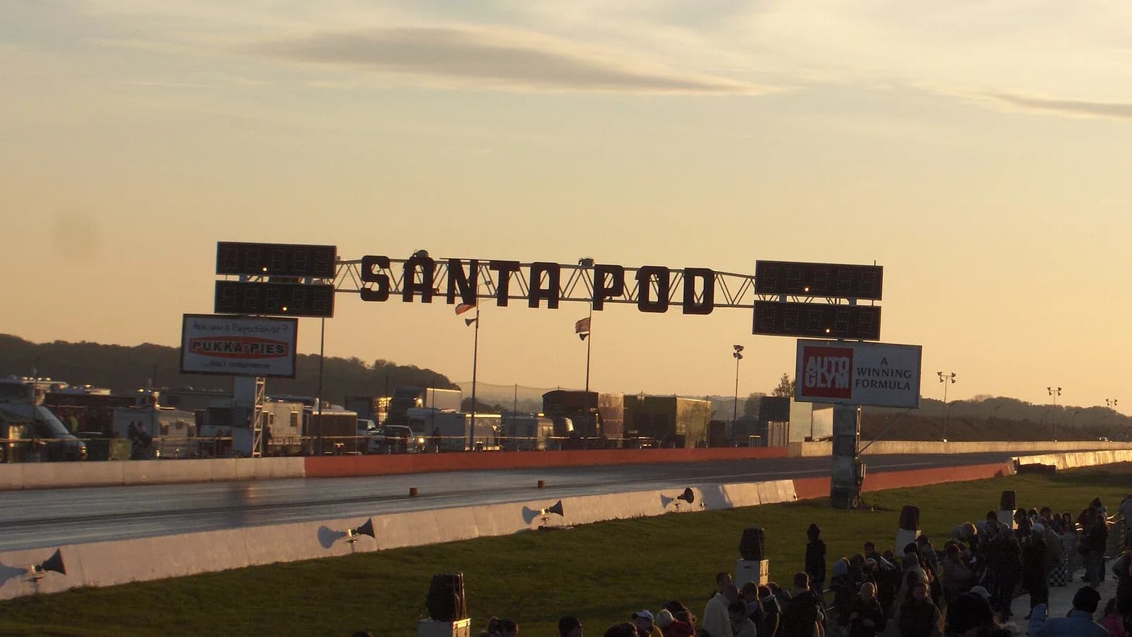 The Santa Pod Raceway sign above an empty drag strip at dusk